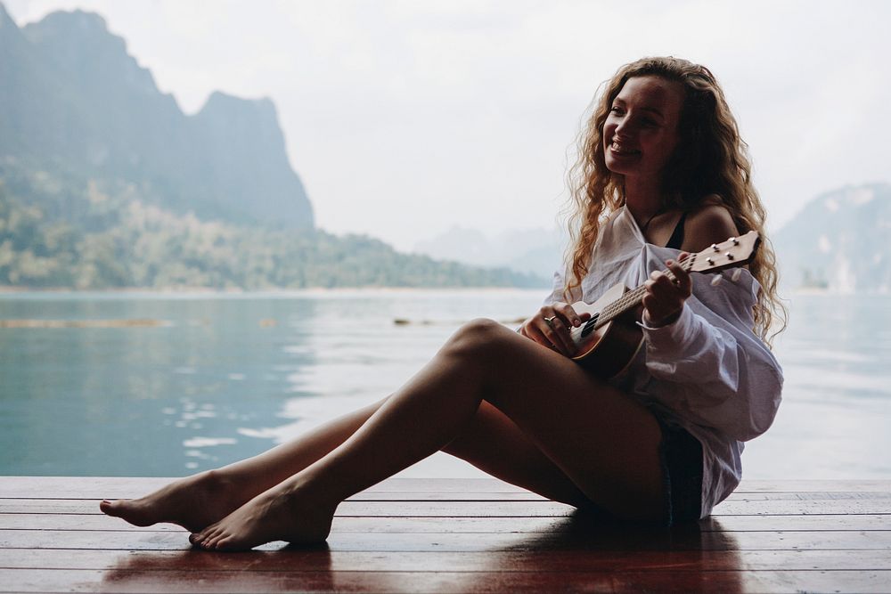 Woman playing ukulele by the water