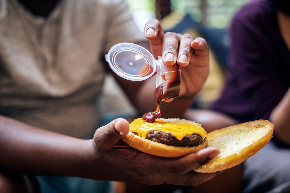 Man adding some ketchup to a burger