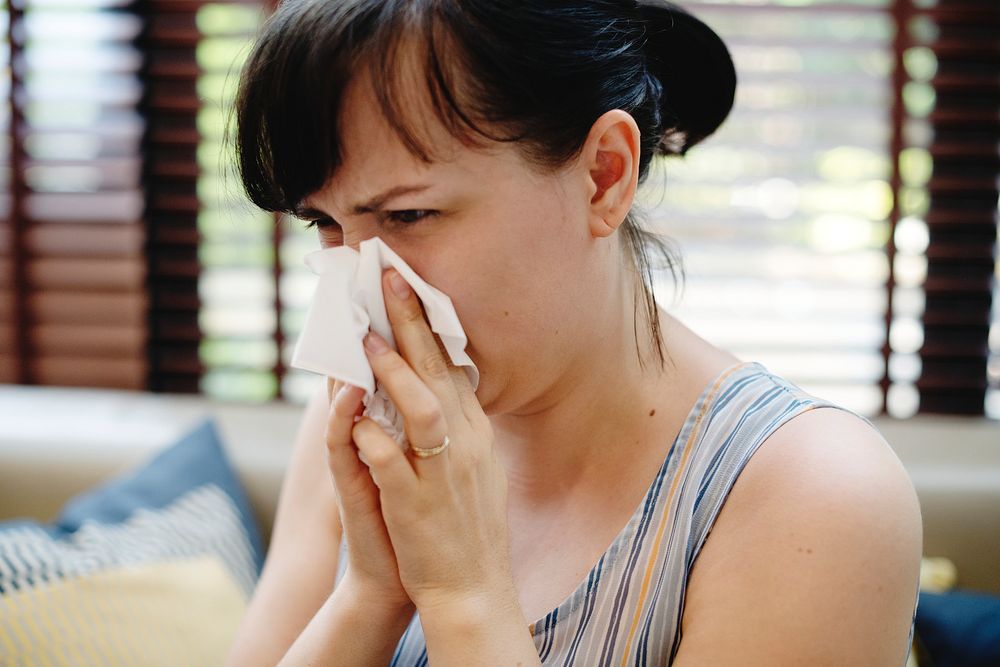 Sick woman sneezing into tissue