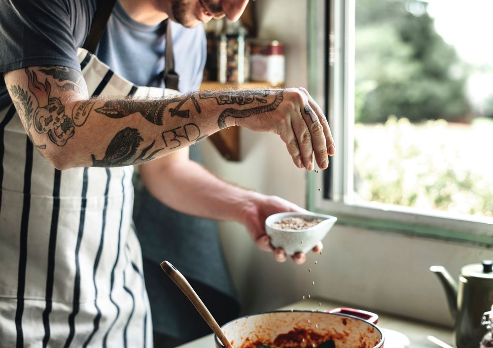 Tattooed man cooking in a countryside kitchen