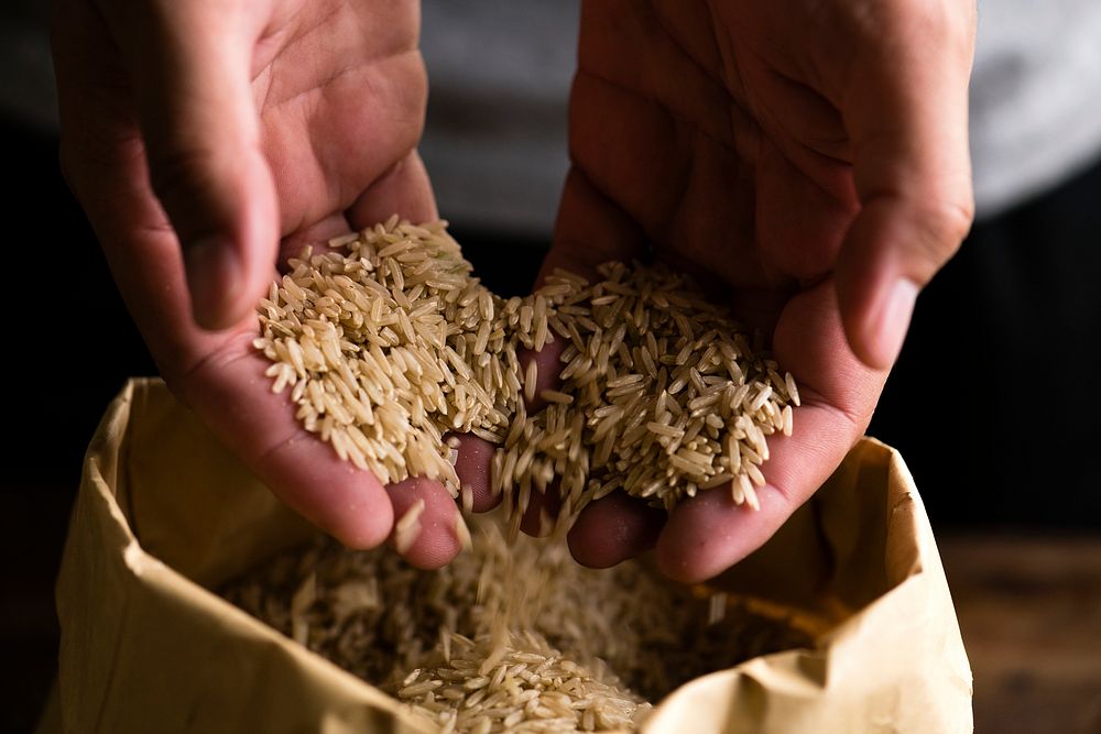 Rice slipping from hands into a paper bag
