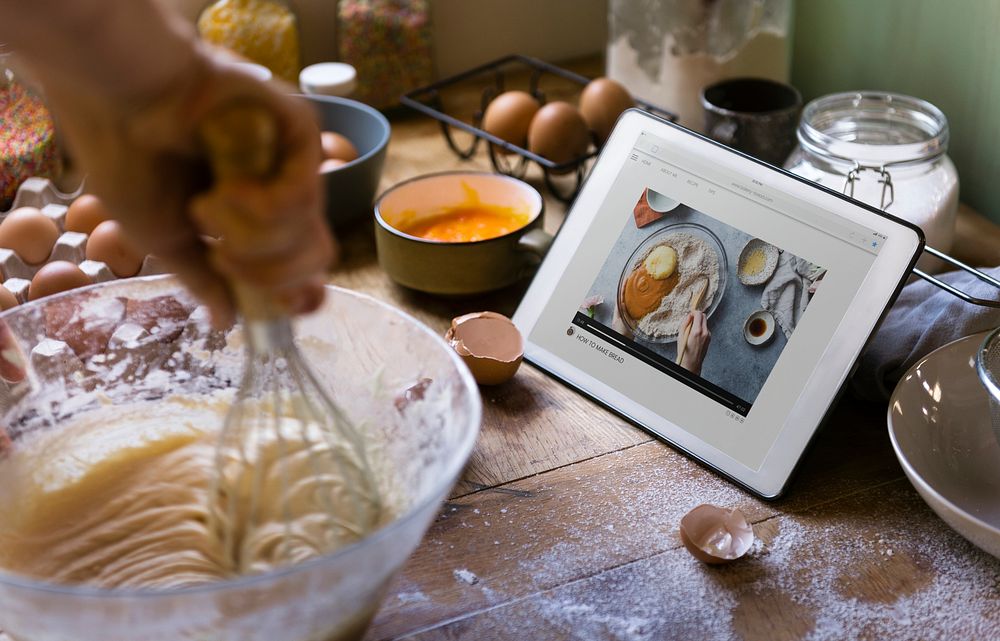 Woman whisking while looking at a recipe on a tablet