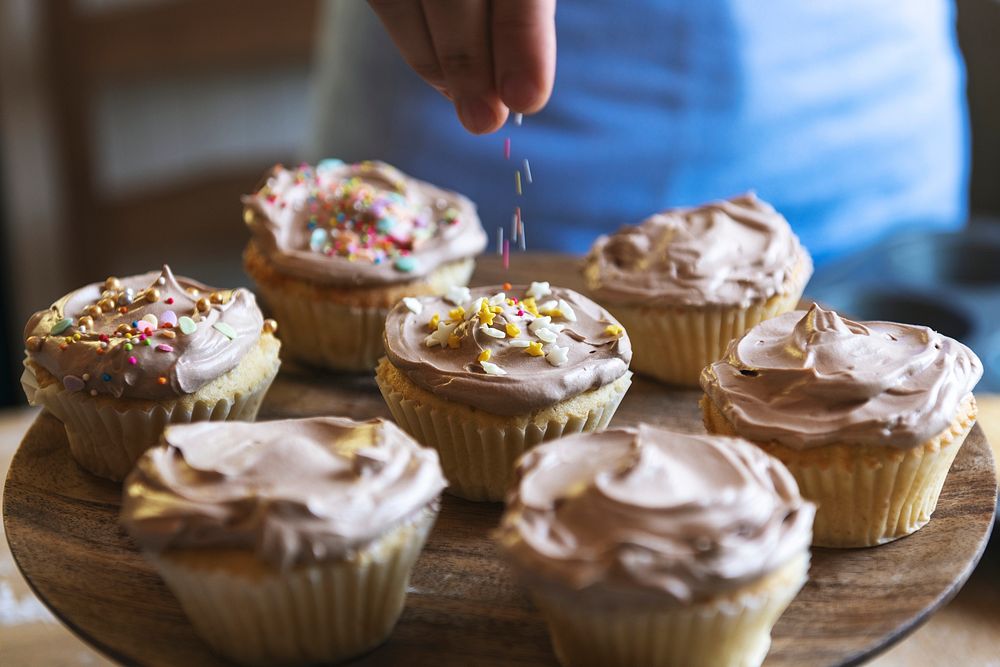 Hand adding sprinkles to chocolate cupcake food photography recipe idea