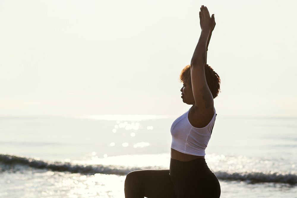 African American woman practicing yoga at the beach