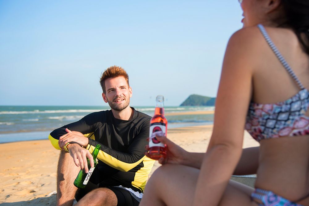 Couple relaxing with beers on the beach