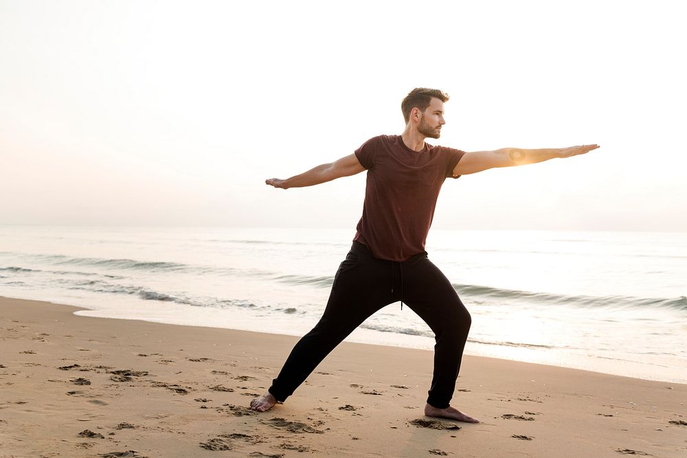 Man practicing yoga on the beach
