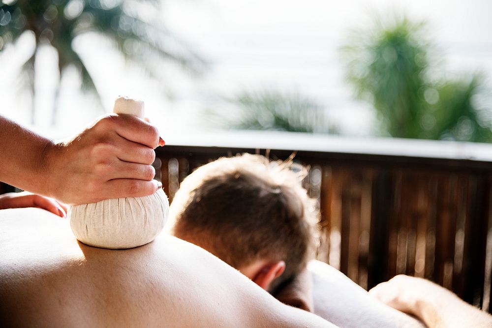 Man having an herbal compress massage at a spa