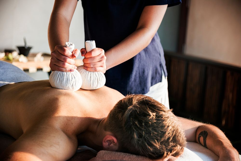 Man having a herbal compress massage at a spa