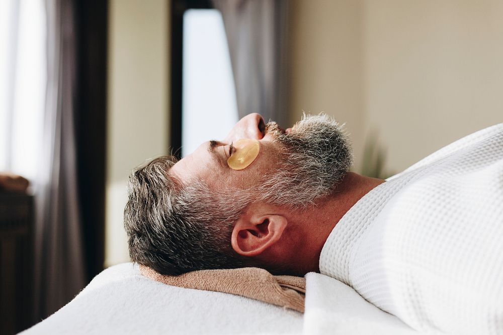 Man relaxing with a golden eye mask treatment