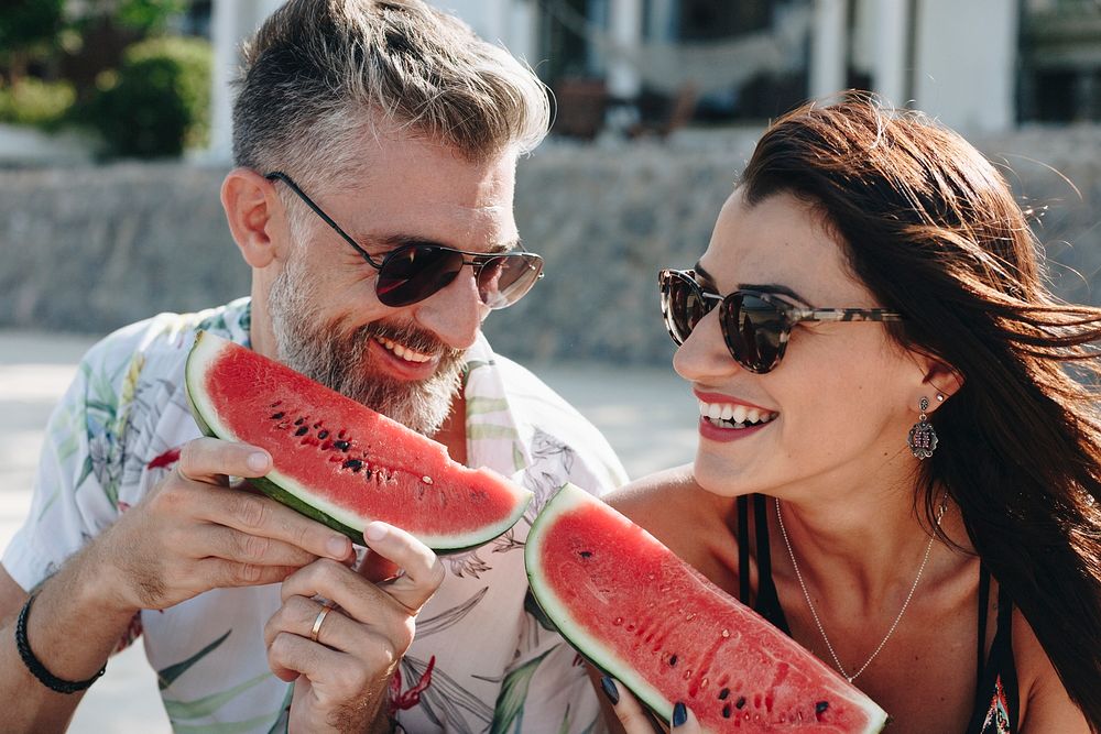 Couple eating watermelon at the beach