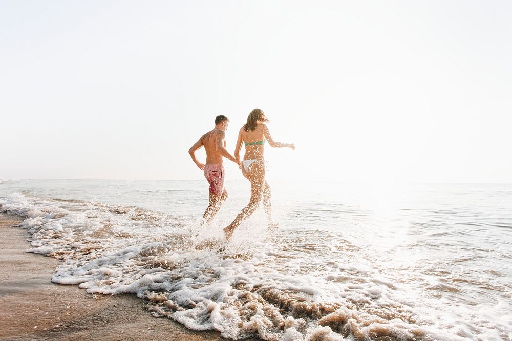 Happy couple running into the water