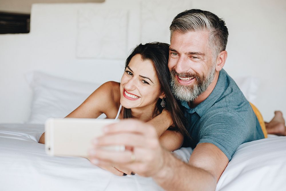 Honeymooners taking a selfie in bed