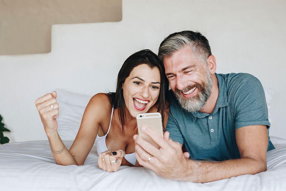 Couple using a smartphone in bed