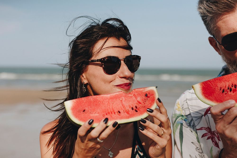 Couple eating watermelon at the beach