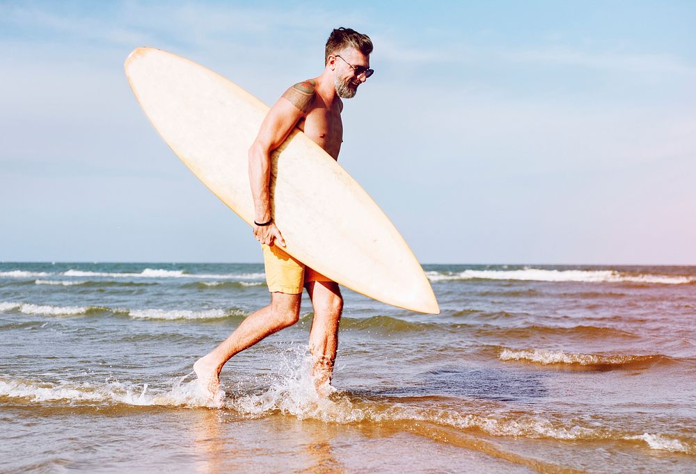 Mature man carrying a surfboard
