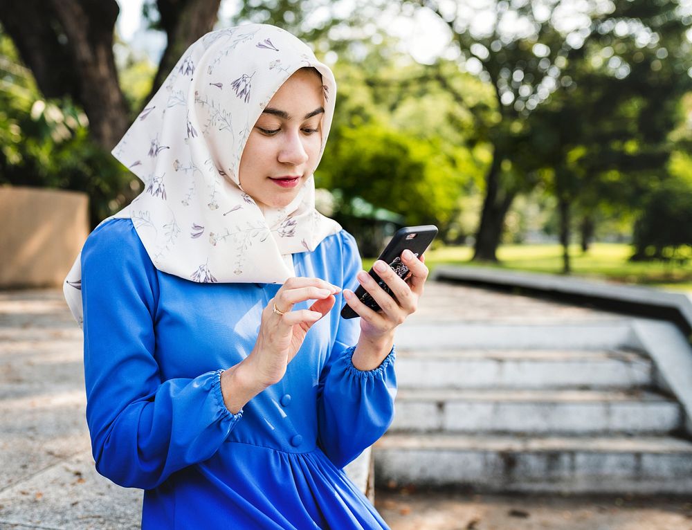 Muslim woman using a smartphone in the park