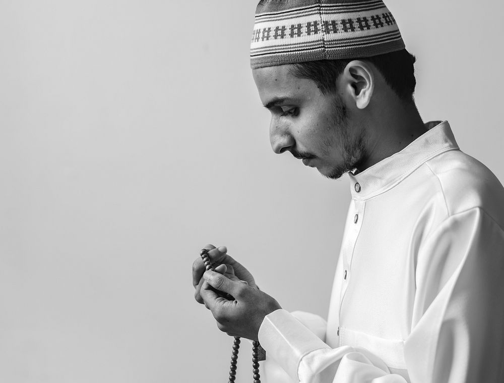 Muslim man using misbaha to keep track of counting in tasbih