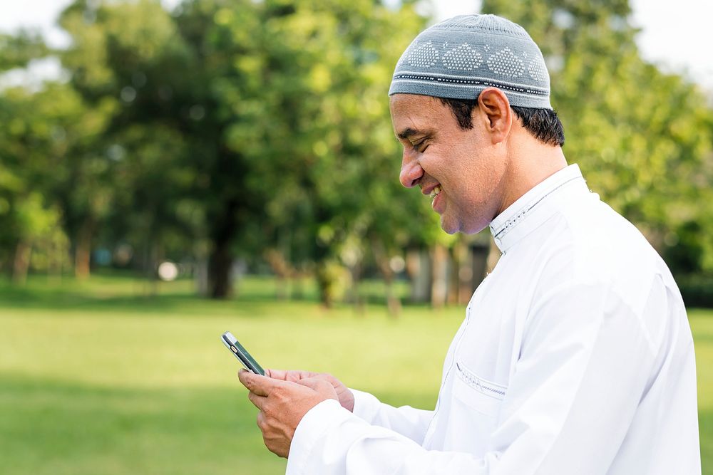 Muslim man using a smartphone in the park