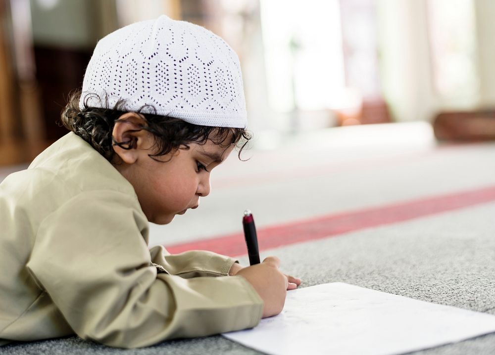 Little boy playfully drawing in a mosque during Ramadan