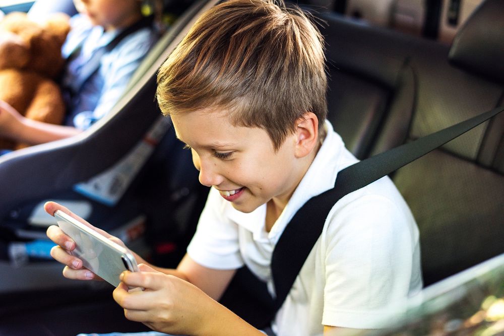 Boy playing on a smartphone in the car