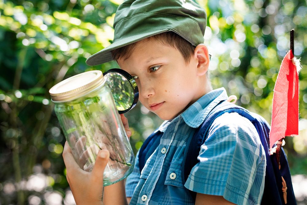 Boy examining a plant with a magnifying glass