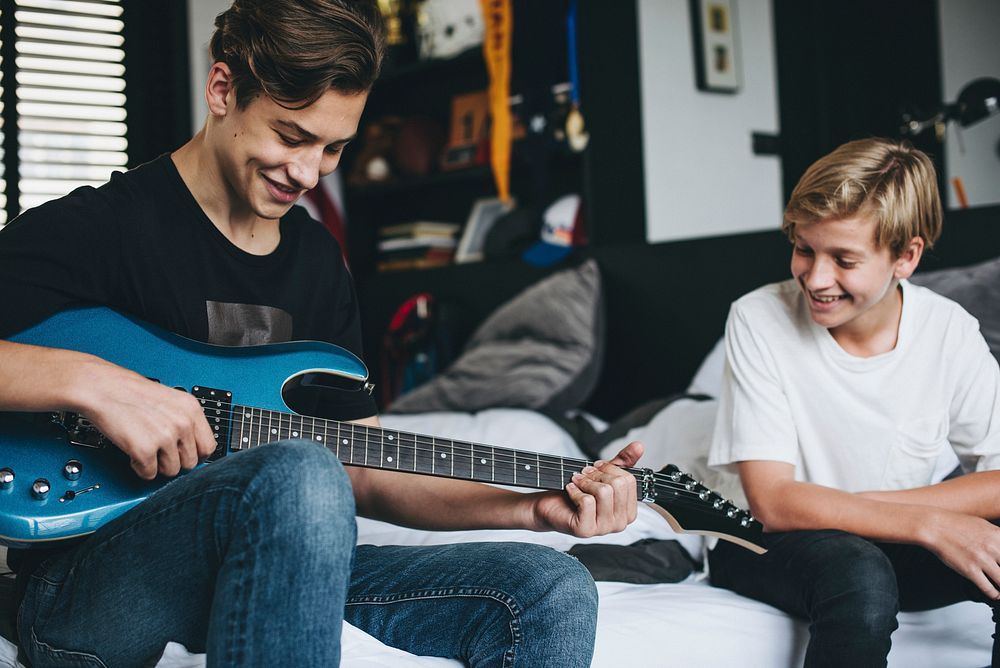 Boys playing the guitar in bed