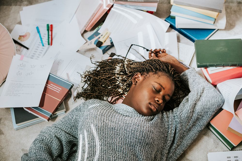 Girl sleeping on a pile of books and paper