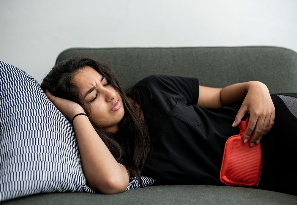 Young girl with using a hot compress on her stomach