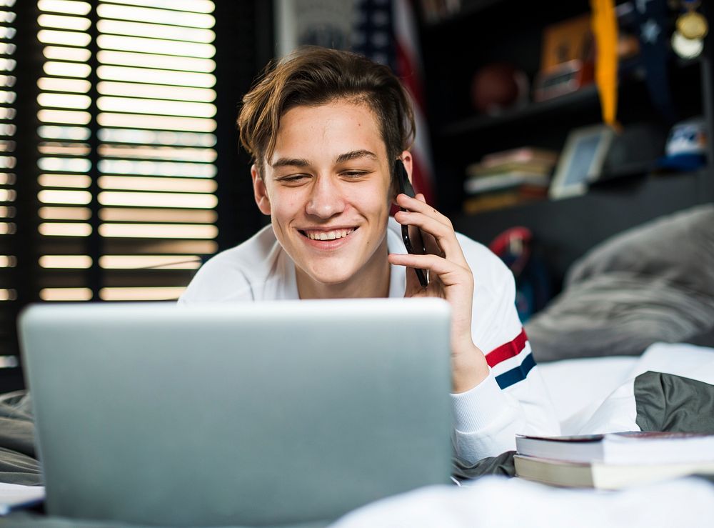 Teenage boy with laptop talking on the cell phone