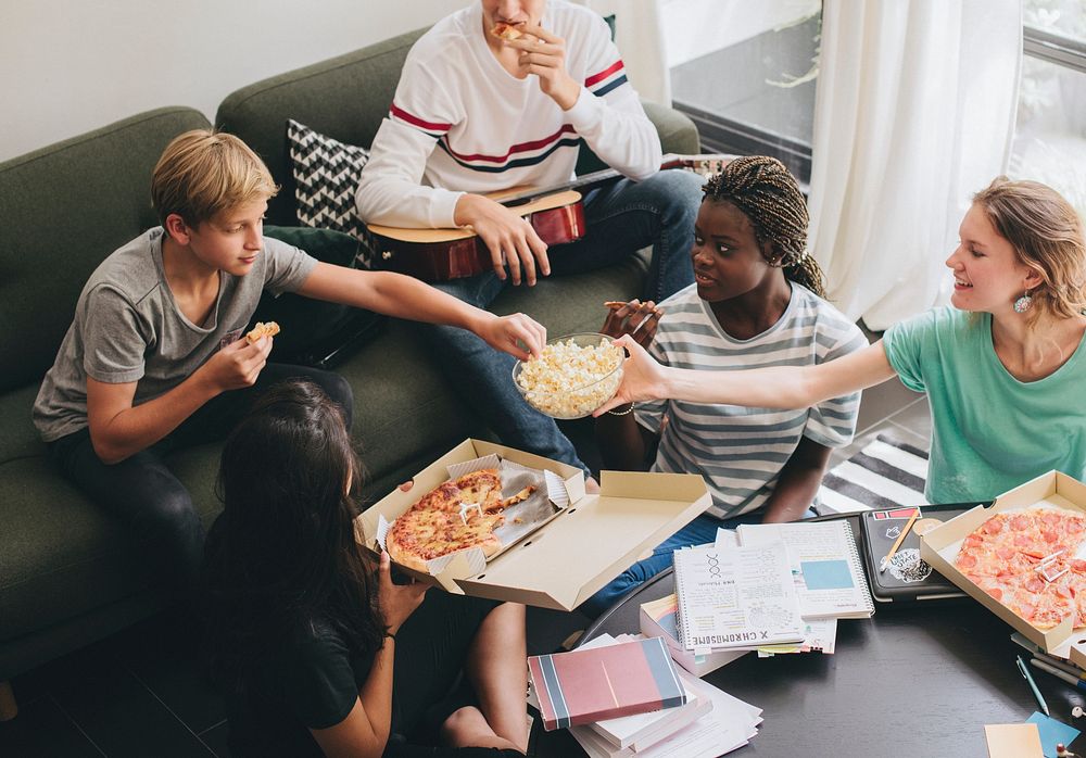 Friends hanging out in the living room eating pizza
