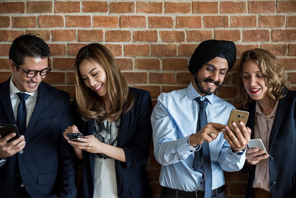 Business people standing in a row using smartphones