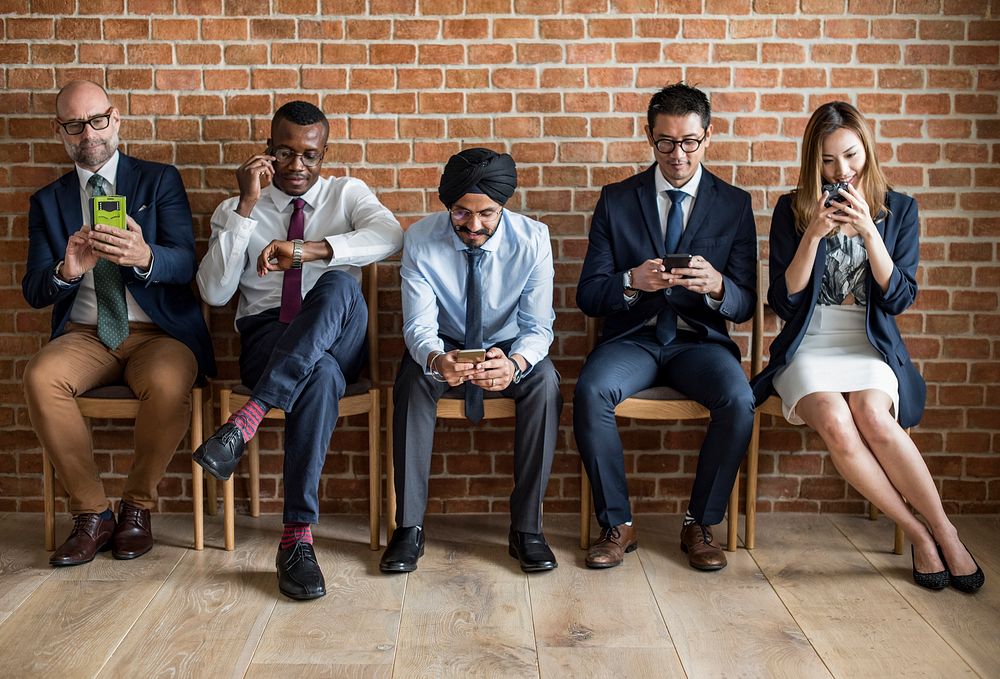 Business people sitting in a row using smartphones