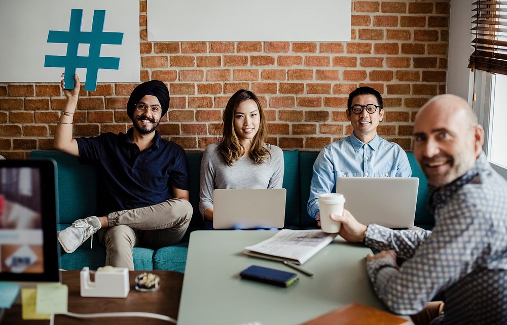 Diverse office workers holding a hashtag symbol