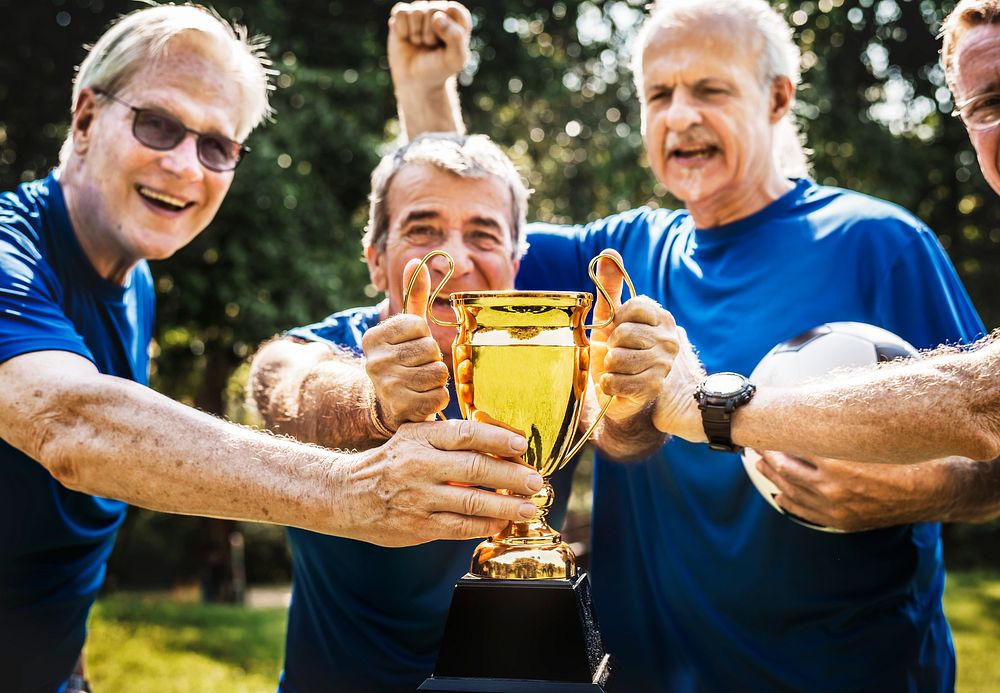 Team of mature football players winning the cup