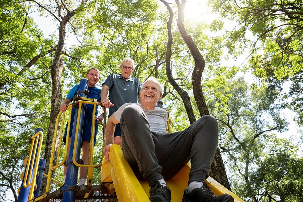 Senior men playing at a playground slide