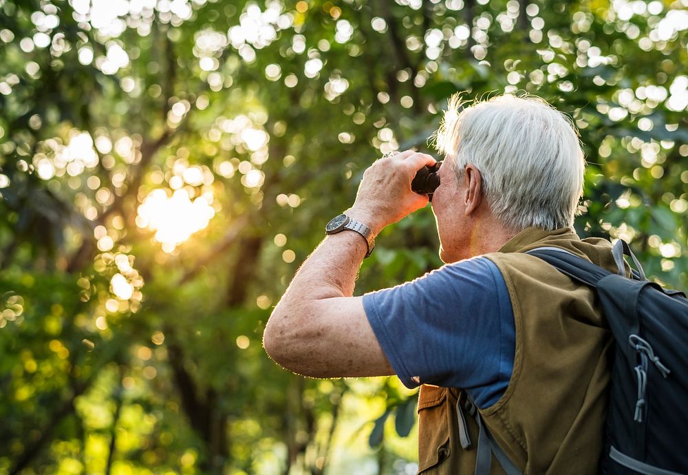 Elderly man watching birds with binoculars