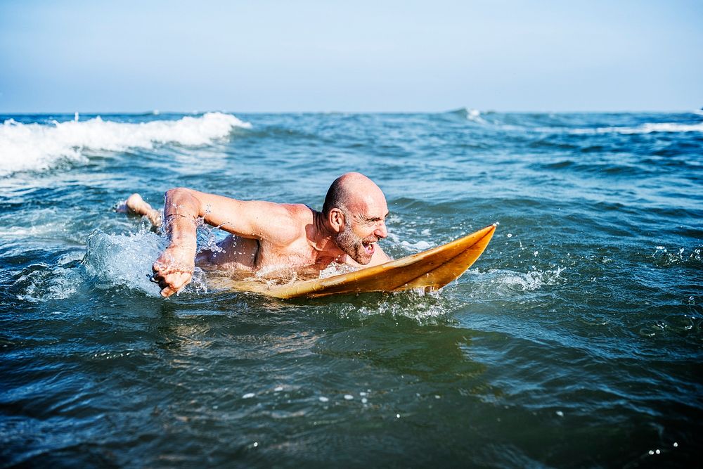 A senior man on a surfboard
