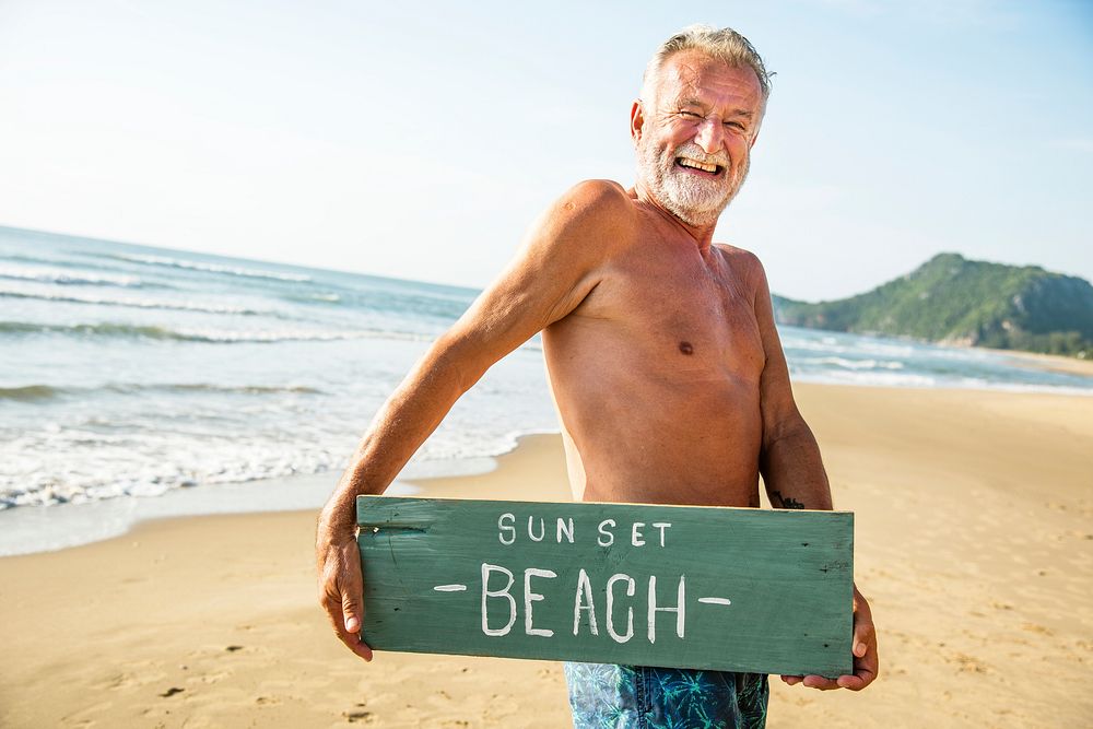 Senior man holding a signboard at the beach