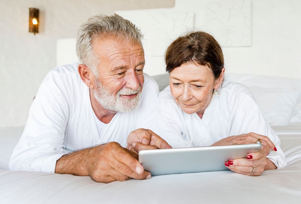 Senior couple using a tablet in bed