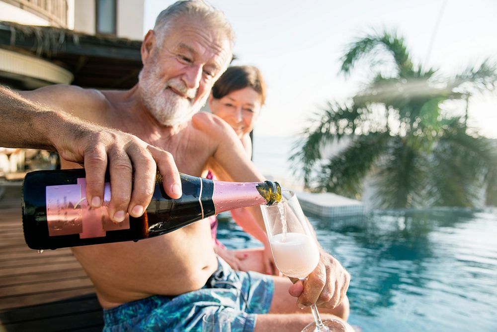 Senior couple drinking prosecco in a swimming pool