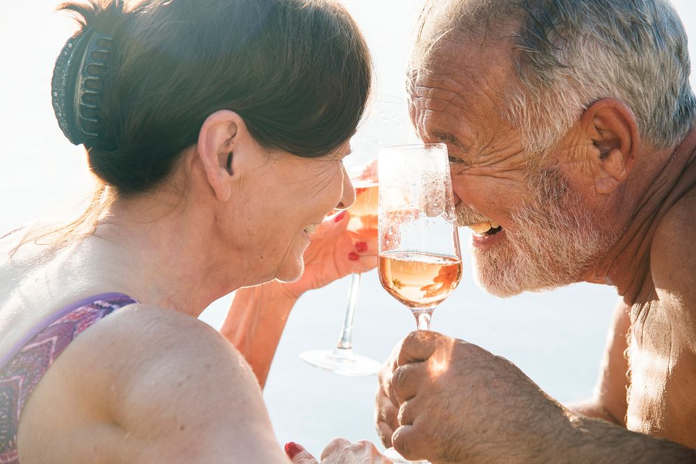 Senior couple drinking prosecco in a swimming pool