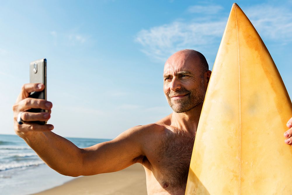 Man holding surfboard taking selfie