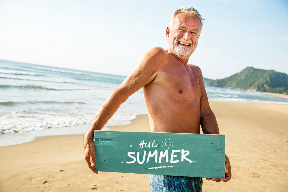 Senior man holding a signboard at the beach