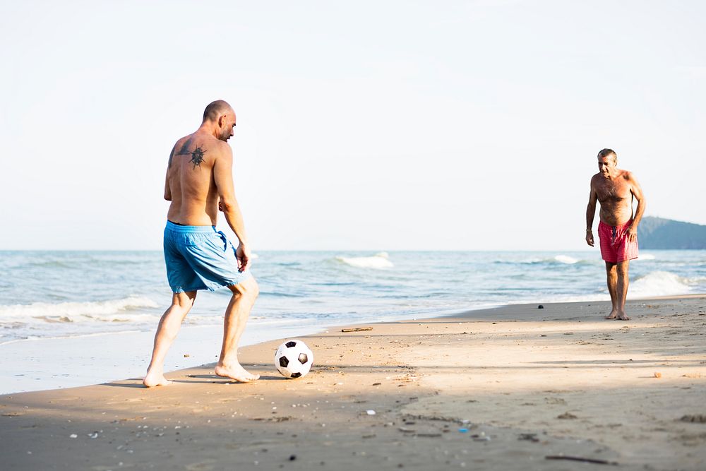 Men playing football at the beach