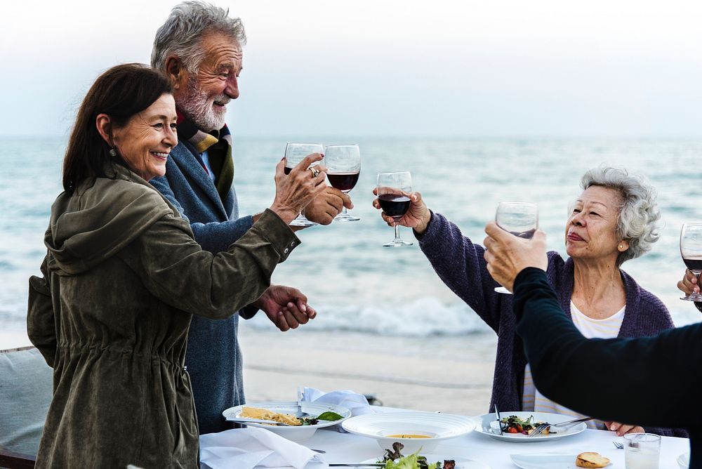 Mature friends drinking wine at the beach