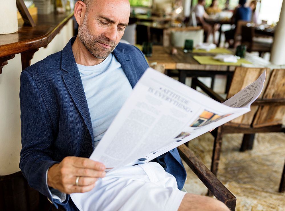 Casual man reading a newspaper at a restaurant