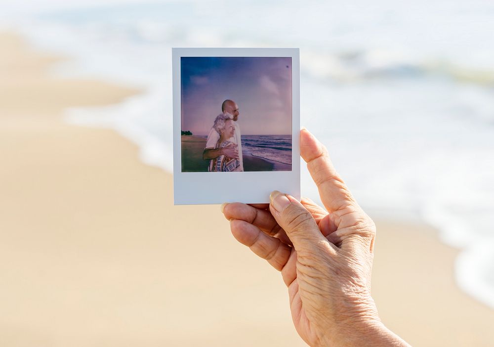 Old lady holding a photograph at the beach