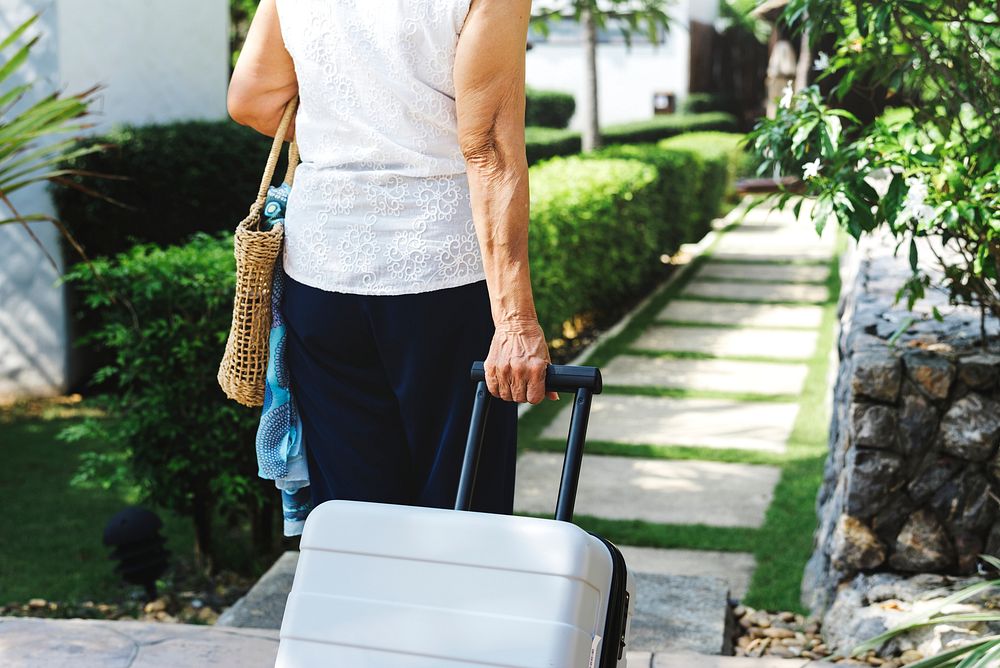 Senior woman pulling suitcase and walking