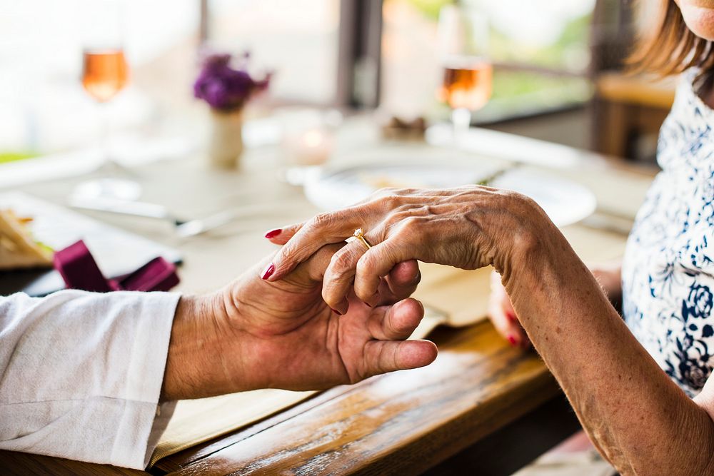 Seniors holding hands at a table