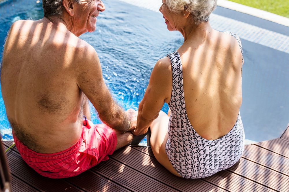 Senior couple holding hands by the swimming pool